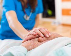 Nurse touching patient's hands