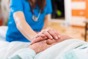 Nurse touching patient's hands